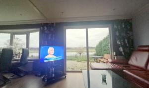 a living room with a tv with a woman on it at SUNBI-Chalet in Lathum