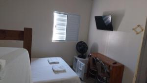 a bedroom with a bed and a table and a window at Oriental Hotel in Sorocaba