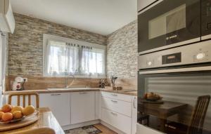 a kitchen with white cabinets and brick walls at 3 Bedroom Gorgeous Home In Rochefort in Rochefort