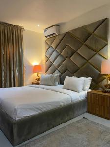 a bedroom with a large bed with a large headboard at Swiss pearl continental hotels and apartments in Abuja