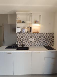 a kitchen with white cabinets and a tile wall at Sun-up in Rogoznica