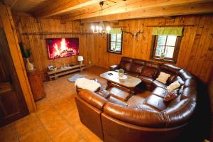 a living room with a leather couch and a tv at Drevenica Tatry No 1 in Liptovský Mikuláš