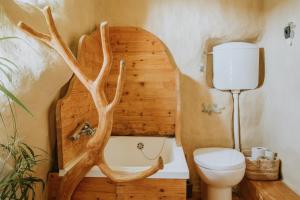 a bathroom with a toilet and a tree branch wall at Private Eco Cottage in Nature in Šulinci