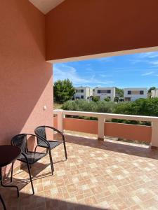 d'un balcon avec des chaises et une vue sur les bâtiments. dans l'établissement Apartman Jim, à Vir