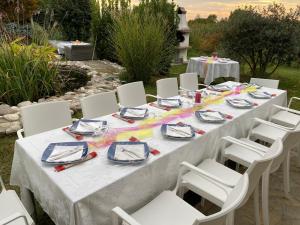 a long table with white chairs and plates and napkins at Pool & Garden Villa Lelia in Mirano