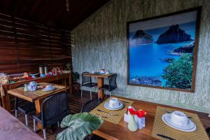 a room with a table and chairs and a tv at Pousada Flor de Noronha in Fernando de Noronha