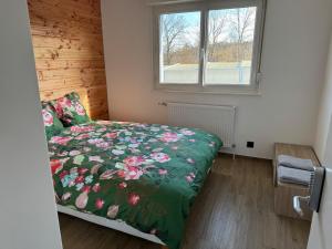 a bedroom with a bed with a floral comforter and a window at Maison 8 personnes 4 Chambres Doubles - Piscine in Anould +44 photos