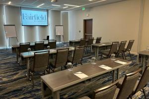 a conference room with tables and chairs and a screen at Fairfield by Marriott San Jose Airport Alajuela in Alajuela City