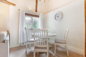 ein Esszimmer mit Tisch und Stühlen und einer Uhr in der Unterkunft Cosy 1 Bedroom Cottage, The Old Thatch, Bredon in Bredon