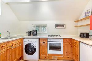 eine Küche mit Waschmaschine und Spüle in der Unterkunft Cosy 1 Bedroom Cottage, The Old Thatch, Bredon in Bredon