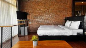 a bedroom with a bed and a brick wall at Bed Loft Cafe in Khon Kaen