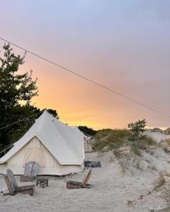 a tent and chairs on a beach with a sunset at Dunes Beach Camp in Neksø