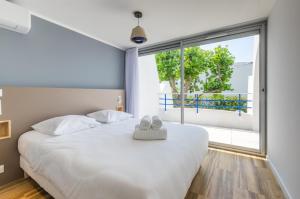 a bedroom with a white bed and a large window at MY Hôtel Résidences - La Grande-Motte in La Grande Motte