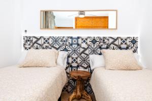 a bedroom with two beds and a mirror on the wall at Calas Beach Corralejo in Corralejo