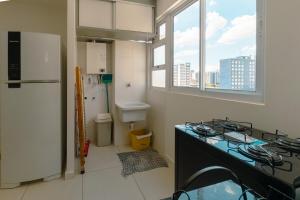 a kitchen with a sink and a refrigerator in a room at Apartamento Funcional no Coração da Cidade in Maringá