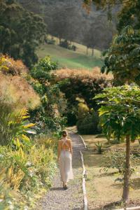 a woman in a white dress walking down a path at Lumbre Forest Lodge in Salento +49 photos