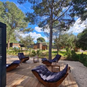 a deck with chairs and tables and a tree at Chalet de Prestige à Agde, Résidence privée avec Spa et Piscines proche plages in Agde