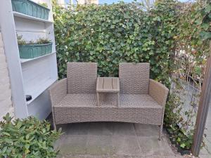 two wicker chairs sitting in front of a hedge at Huisje Louis in Zandvoort