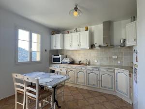 a kitchen with white cabinets and a table and a refrigerator at Maison charmante près du lac d'Esparron, 2 chambres, parking - FR-1-822-10 in Esparron-de-Verdon