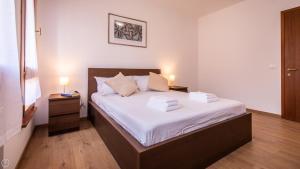 Un dormitorio con una cama con sábanas blancas y dos lámparas. en Italianway - Aquileia 53, en Udine