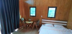 una camera con un letto e un tavolo e due finestre di Khu Nghỉ Dưỡng Lộc Nam Hill Bảo Lộc a Pro Lach (2)