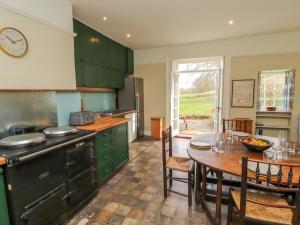 a kitchen with green cabinets and a table and a dining room at Westward Park in Wigton