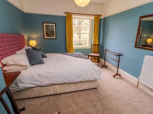 a bedroom with a bed with blue walls and a window at Westward Park in Wigton