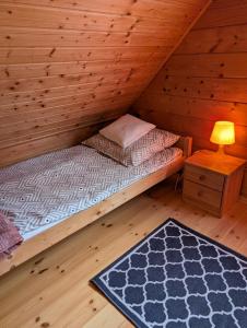 Posto letto in camera in legno con lampada e tappeto. di Domek letniskowy OAZA a Ryn