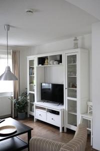 a living room with a white entertainment center with a television at Ferienwohnung am Brunnen in Titisee-Neustadt +25 photos