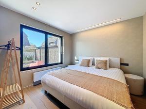 a bedroom with a bed and a large window at Villa Hélène - 2 newly renovated flats for rent together or separately in Koksijde