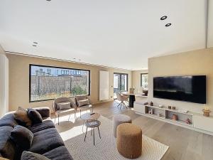 a living room with a couch and a tv at Villa Hélène - 2 newly renovated flats for rent together or separately in Koksijde