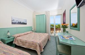 a hotel room with two beds and a desk and a window at Da Giorgio in Capri