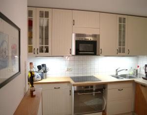 a kitchen with white cabinets and a sink and a microwave at Ferienwohnung im Haus Schwedes in Titisee-Neustadt