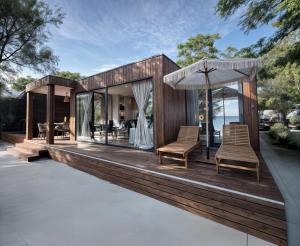 a house with a deck with chairs and an umbrella at Luxury Seaside Villa Privlaka with Jacuzzi and sauna - 10 Gardens - Beach & Relax Croatia in Privlaka