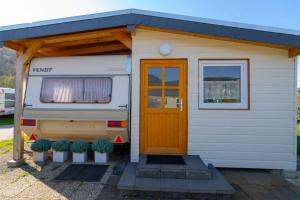 尼德根Mietwohnwagen 1007的一辆白色的小大篷车,有门和一些植物