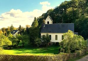 a white church with a steeple on top of a yard at Die Malche Gäste und Tagungshaus Villa App 13 in Alaunwerk