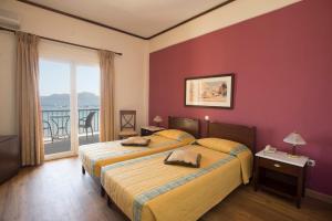 a hotel room with two beds and a balcony at Methoni Beach Hotel in Methoni