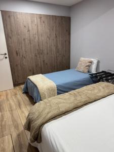 a bedroom with two beds and a wooden wall at Meu Refugio Apartamento in Silveira