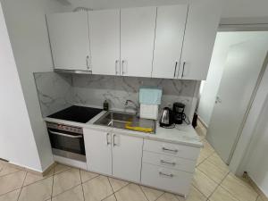 a kitchen with white cabinets and a sink at Comfort Apartments Promenade in Sarandë