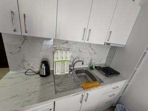 a kitchen counter with a sink and white cabinets at Comfort Apartments Promenade in Sarandë