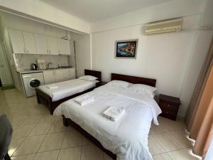two beds in a hotel room with a kitchen at Comfort Apartments Promenade in Sarandë