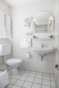 a white bathroom with a toilet and a sink at Kloster-Remise Wöltingerode in Goslar