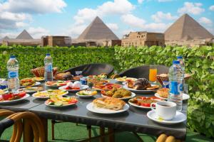 a table full of food with the pyramids in the background at Giza Pyramids view hotel in Giza