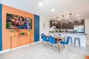 Designer Decorated - 3 Bedroom NEAR DISNEY في كيسيمي: مطبخ وغرفة طعام مع طاولة وكراسي زرقاء