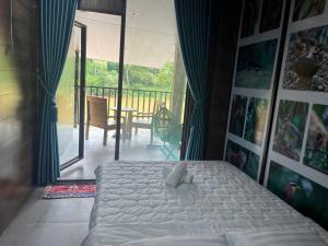 a bedroom with a bed and a balcony with a table at Floor river view in Cat Tien