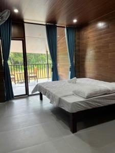 a bedroom with a large bed and a balcony at Floor river view in Cat Tien