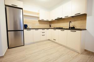 a kitchen with white cabinets and a stainless steel refrigerator at Apartments by Bog Flor in Suceava