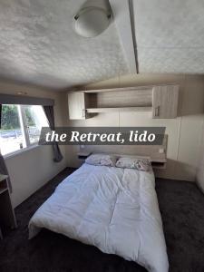 un dormitorio con una cama con un cartel que lee la información del retiro en The Retreat Lido Beach - Lido Beach Prestatyn, en Prestatyn