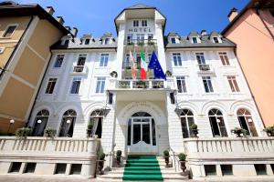 een wit gebouw met vlaggen erop bij Hotel Croce Bianca in Asiago