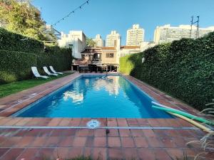 a swimming pool in a yard with two lawn chairs at Espectacular casa de 4 dormitorios y 5 baños para 12 personas, en la mejor zona de Montevideo in Montevideo